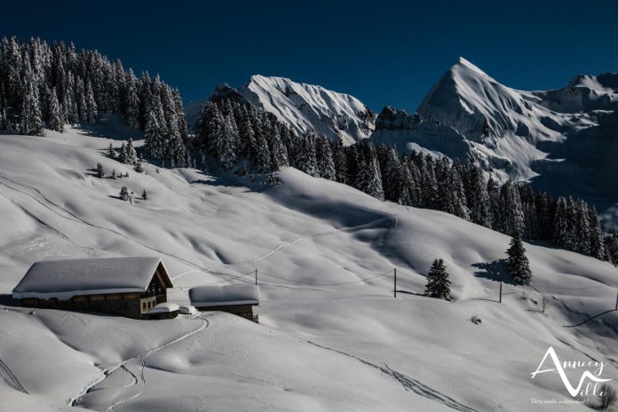 Vue sur les montagnes du Grand Bornand et un chalet après une chute de neige