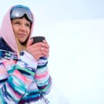 Femme qui se réchauffe avec une boisson après le ski