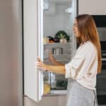 Jeune femme prenant de la nourriture du frigo