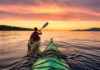 Kayak : 5 spots incroyables à moins de 2 heures d’Annecy Une femme en kayak sur le lac au coucher du soleil