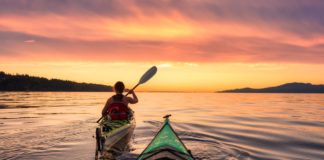 Kayak : 5 spots incroyables à moins de 2 heures d’Annecy Une femme en kayak sur le lac au coucher du soleil
