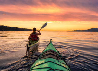 Kayak : 5 spots incroyables à moins de 2 heures d’Annecy Une femme en kayak sur le lac au coucher du soleil