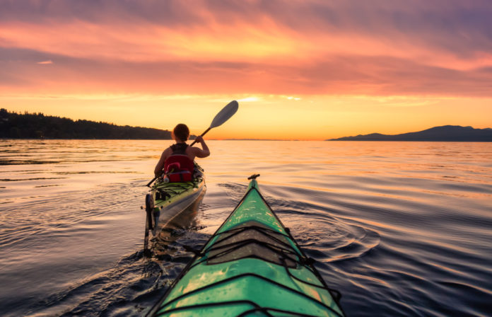 Une femme en kayak sur le lac au coucher du soleil